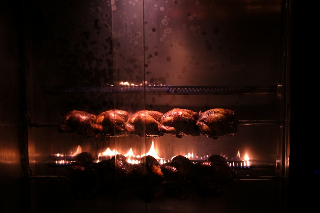 Rosticería con pollos girando sobre fuego
